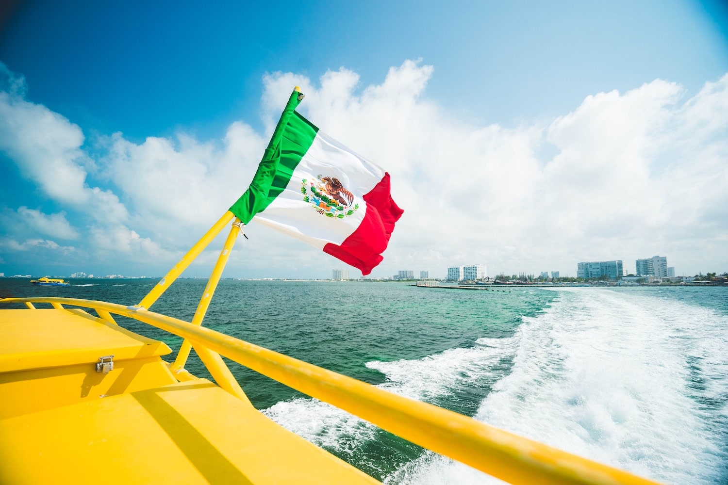 Gay Cancun, Mexico. Boat riding through ocean with flag in view. Overlooking the city of Cancun.